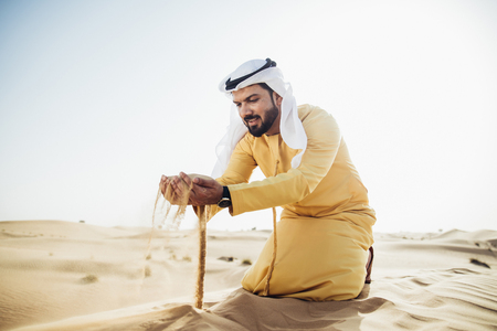 Man wearing traditional uae clothes spending time in the desertの写真素材