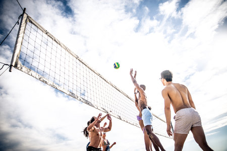 Group of friends playing beach volley - Multi-ethic group of people having fun on the beachのeditorial素材