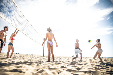 Group of friends playing beach volley - Multi-ethic group of people having fun on the beachのeditorial素材