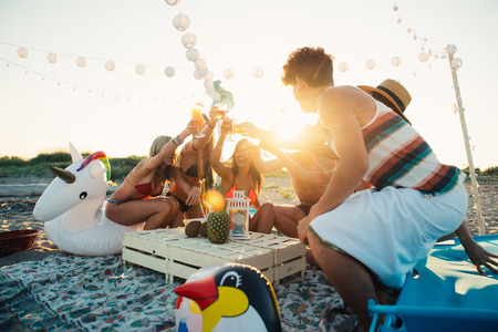 Group of friends making party on the beach at sunset timeの写真素材