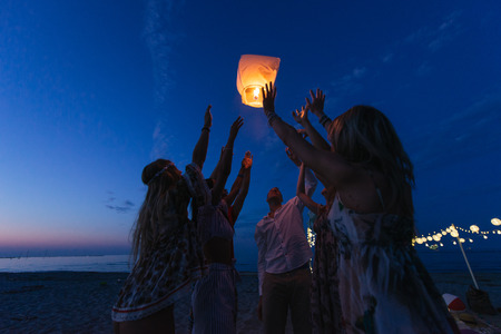 Group of friends making party on the beach at sunset timeの写真素材