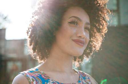 Beautiful latin woman with curly hair, portrait set in the cityの写真素材
