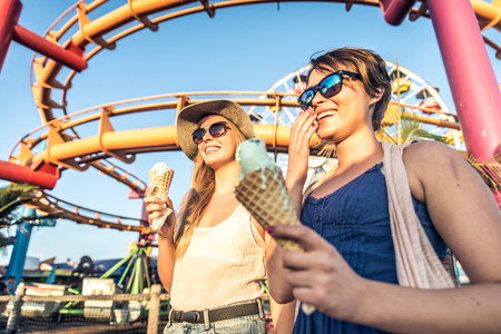 Two young women eating ice cream of Santa Monica pier and having fun