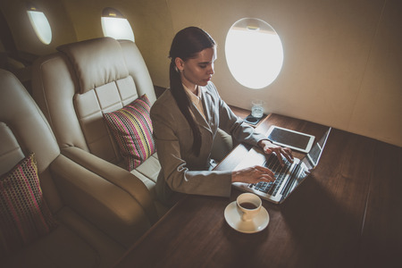 Business woman traveling and working on the private jetの写真素材