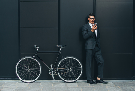 Handsome young business man with his modern bicycle.の写真素材