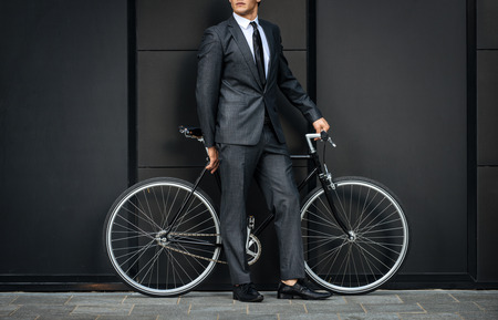 Handsome young business man with his modern bicycle.の写真素材