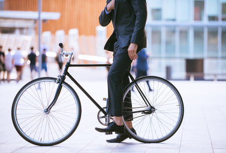 Handsome young business man with his modern bicycle.の写真素材