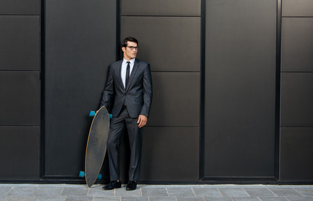 Handsome young business man with his modern longboardの写真素材