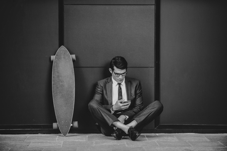 Handsome young business man with his modern longboardの写真素材