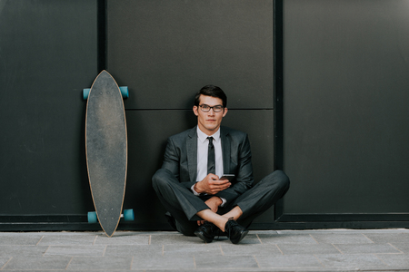 Handsome young business man with his modern longboardの写真素材