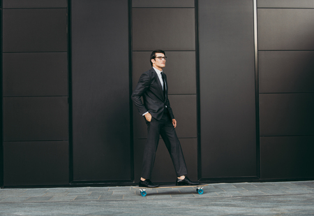 Handsome young business man with his modern longboardの写真素材