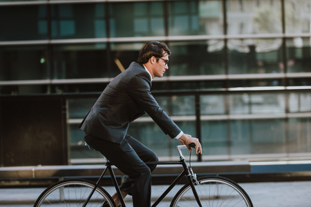Handsome young business man with his modern bicycle.の写真素材