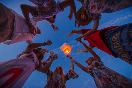 Young millenials holding and igniting sky lantern - Lantern festival on the beachの写真素材