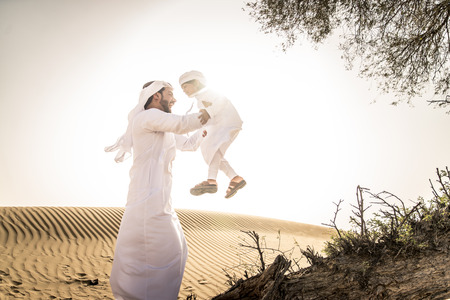 Happy family playing in the desert of Dubai -  Playful father and his son having fun outdoorsの写真素材