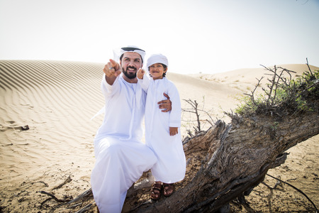 Happy family playing in the desert of Dubai -  Playful father and his son having fun outdoorsの写真素材