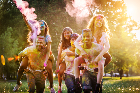 Group of happy friends playing with holi colors in a park - Young adults having fun at a holi festival, concepts about fun, fun and young generationの写真素材