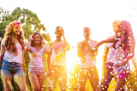 Group of happy friends playing with holi colors in a park - Young adults having fun at a holi festival, concepts about fun, fun and young generationの写真素材