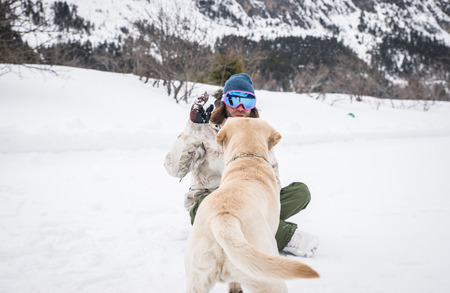 Owner and his dog playing in the snow - Young adult man having fun with his loyal labradorの写真素材