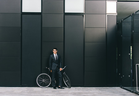 Young handsome man with business suit driving bycicle - Corporate businessman portrait, concepts about business, mobility and lifestyleの写真素材