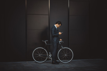 Young handsome man with business suit driving bycicle - Corporate businessman portrait, concepts about business, mobility and lifestyleの写真素材
