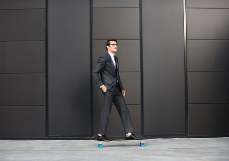 Young handsome man with business suit riding on a longboard - Corporate businessman portrait, concepts about business, mobility and lifestyleの写真素材