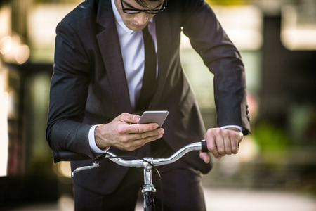 Young handsome man with business suit driving bycicle - Corporate businessman portrait, concepts about business, mobility and lifestyleの写真素材