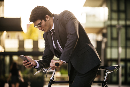 Young handsome man with business suit driving bycicle - Corporate businessman portrait, concepts about business, mobility and lifestyleの写真素材