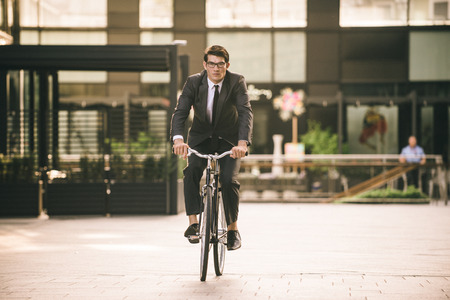 Young handsome man with business suit driving bycicle - Corporate businessman portrait, concepts about business, mobility and lifestyleの写真素材