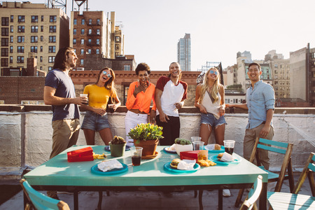 Group of friends spending time together on a rooftop in New York city, lifestyle concept with happy...