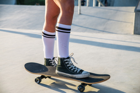 Stylish young woman skating outdoors - Pretty female skater playing with her skateの写真素材
