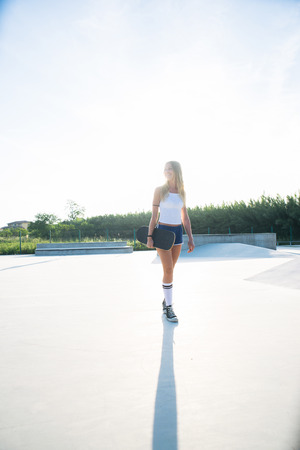 Stylish young woman skating outdoors - Pretty female skater playing with her skateの写真素材