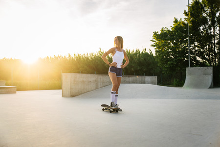 Stylish young woman skating outdoors - Pretty female skater playing with her skateの写真素材