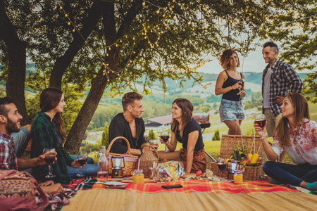 Group of young happy friends having picnic outdoors - People having fun and celebrating while...