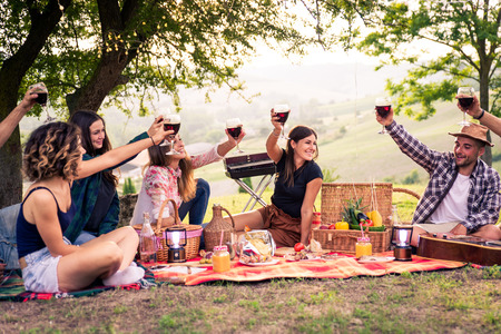 Group of young happy friends having picnic outdoors - People having fun and celebrating while grilling at a barbecue party in a countrysideの写真素材