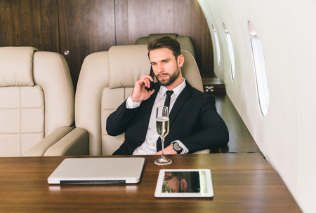 Businessman working while travelling on private jet - Portrait of business people taking a first class flight for work, concepts about business and mobilityの写真素材