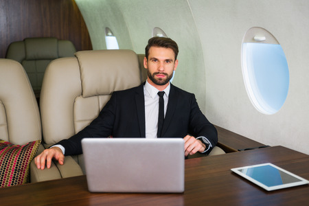 Businessman working while travelling on private jet - Portrait of business people taking a first class flight for work, concepts about business and mobilityの写真素材