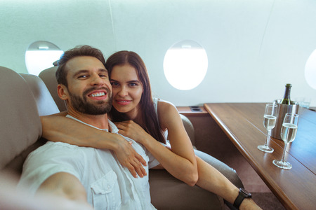 Happy couple travelling on a luxury private jet - Young adults travel on a first class flight, concepts about travel and lifestyleの写真素材