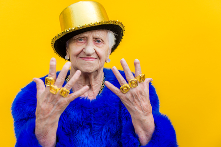 Funny and extravagant senior woman posing on colored background - Youthful old woman in the sixties...