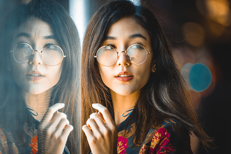 Beautiful mixed race woman posing outdoors, background with blurred neon lightsの写真素材