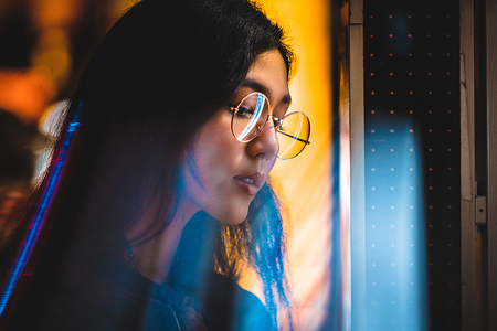 Beautiful mixed race woman posing outdoors, background with blurred neon lights