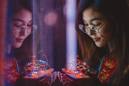 Beautiful mixed race woman posing outdoors, background with blurred neon lights