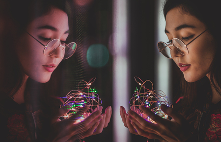 Beautiful mixed race woman posing outdoors, background with blurred neon lightsの写真素材