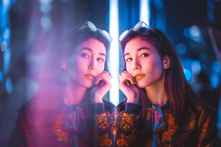 Beautiful mixed race woman posing outdoors, background with blurred neon lights