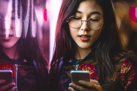 Beautiful mixed race woman posing outdoors, background with blurred neon lightsの写真素材