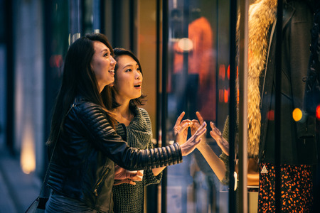 Two girlfriends meeting outdoors and having fun - Japanese people bonding on Tokyo streetsの写真素材