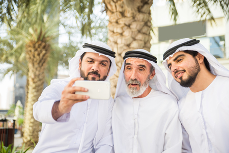 Group of arabian businessmen with kandura meeting outdoors in UAE - Middle-eastern men in Dubaiの写真素材