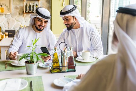 Group of middle eastern men wearing kandora bonding in a cafÃ¨ restaurant in Dubaiの写真素材