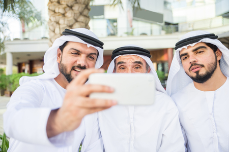 Group of arabian businessmen with kandura meeting outdoors in UAE - Middle-eastern men in Dubaiの写真素材