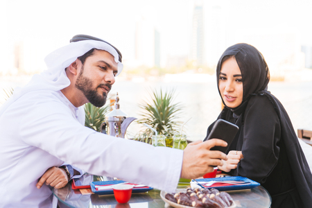 Arabian couple with traditional emirates dress dating outdoors - Happy middle-eastern couple having funの写真素材