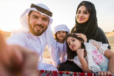 Arabian family with kids having fun in the desert - Parents and children celebrating holiday in the Dubai desrtの写真素材